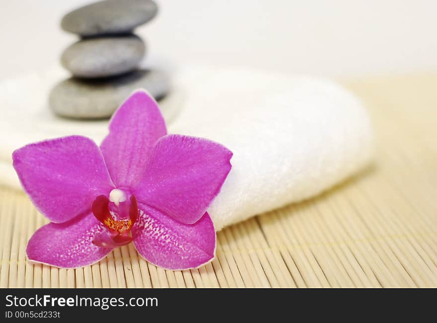 Pebble stones on white towel with orchid flower. Pebble stones on white towel with orchid flower