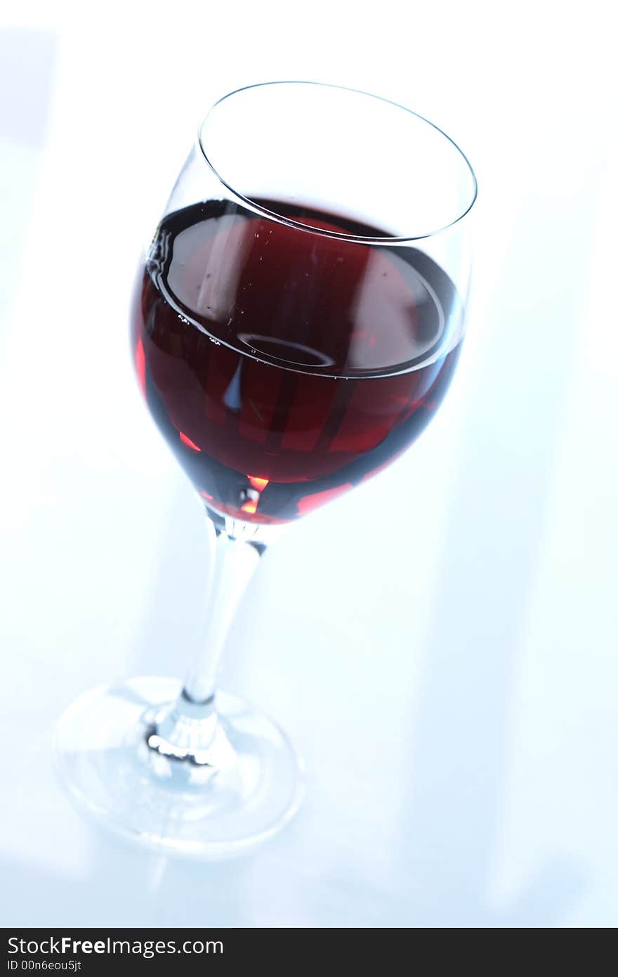 Glass of redwine against lightblue background