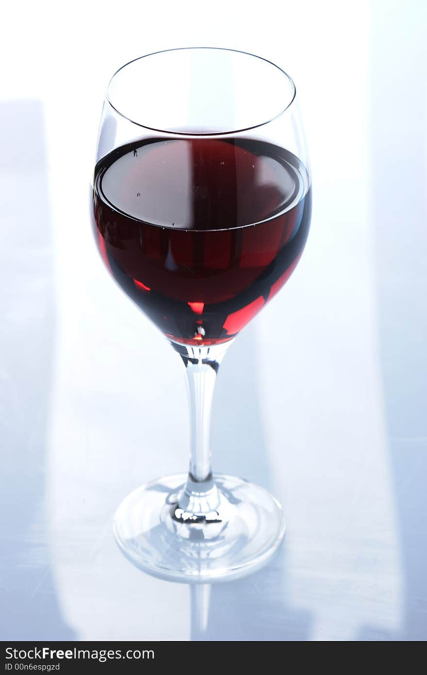 Glass of redwine against lightblue background