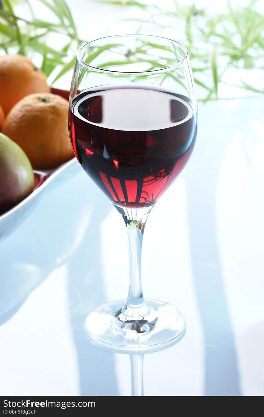 Glass of redwine against some fruits in the background