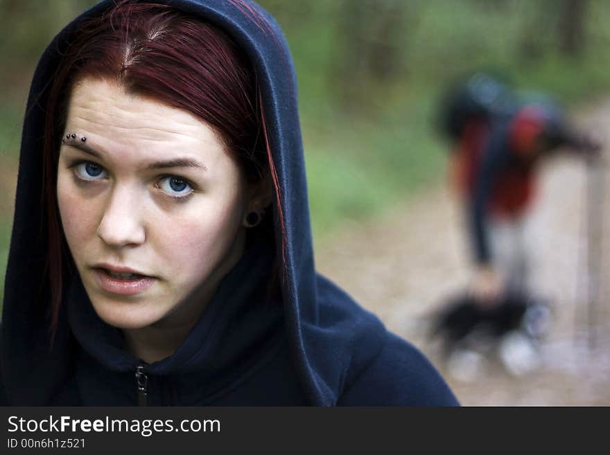 Thirsty girl hiking with a man and his dog in the background. Portrait. Thirsty girl hiking with a man and his dog in the background. Portrait.