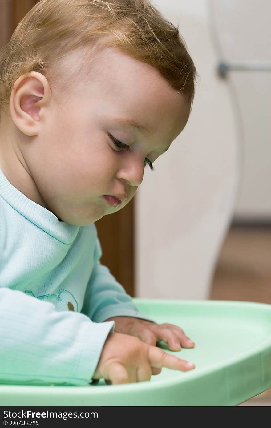 Cute blond child thinking on the green table