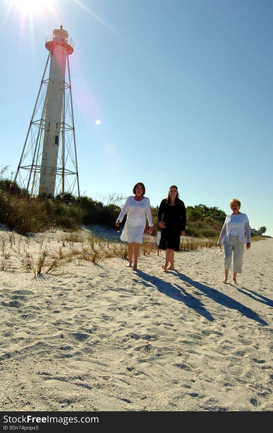 Three women of different generations walking along beach near lighthouse in Boca Grande Florida . Three women of different generations walking along beach near lighthouse in Boca Grande Florida