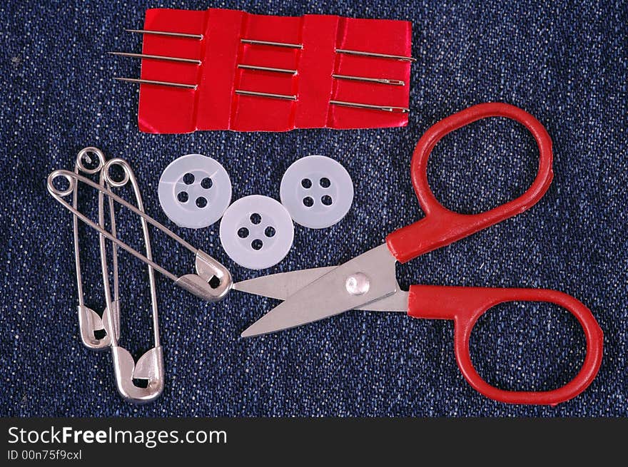 A small sewing kit on denim material.  A macro image taken in a studio. A small sewing kit on denim material.  A macro image taken in a studio.