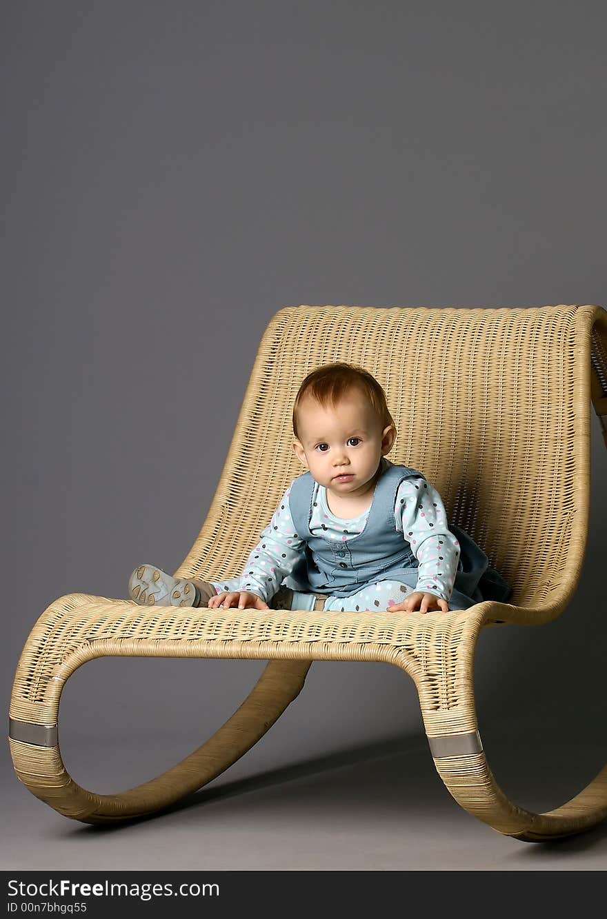 The girl sits on a straw armchair