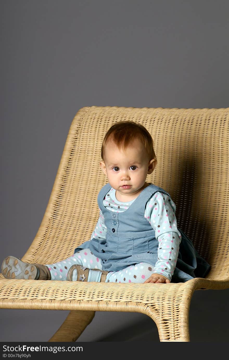 The girl sits on a straw armchair