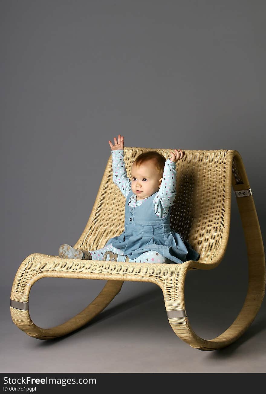 The girl sits on a straw armchair