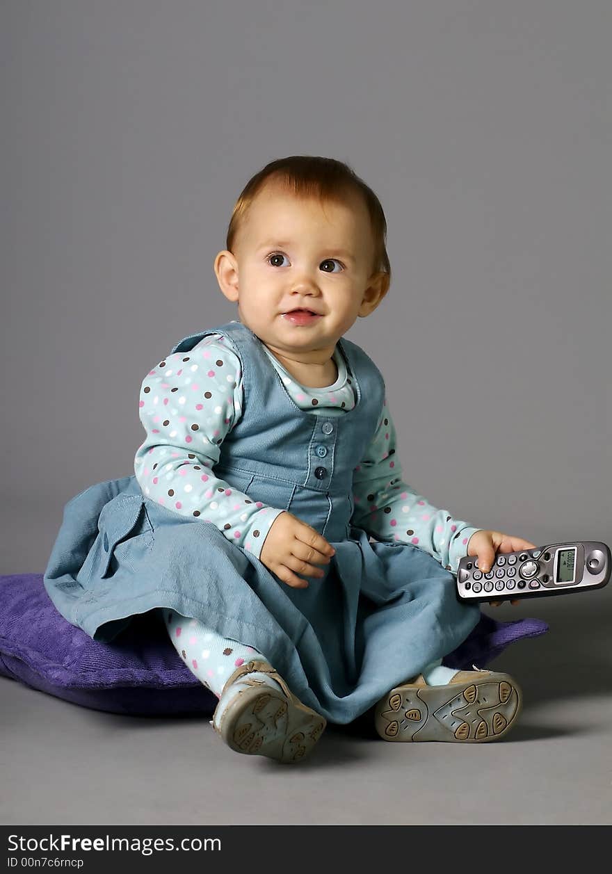 The child calling by phone on a grey background with a smile