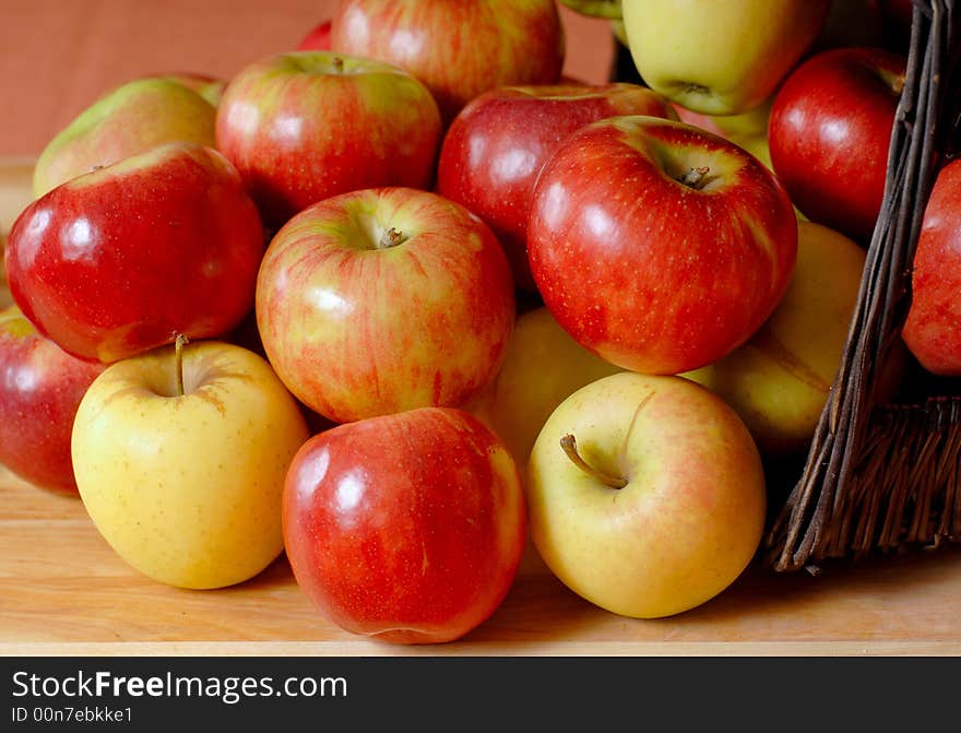 Basketfull of fresh organic apples overflowing onto a table. Basketfull of fresh organic apples overflowing onto a table