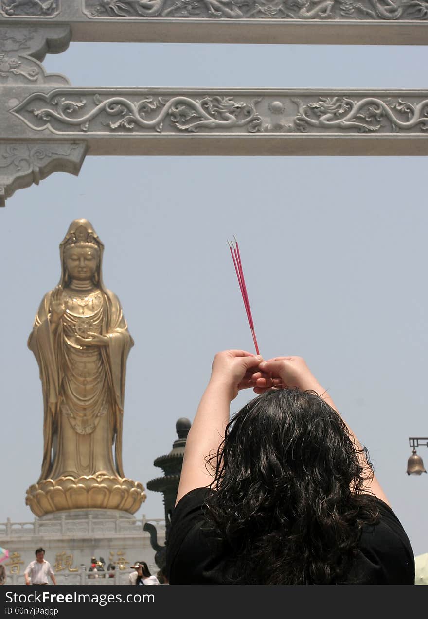 In front of guanyin,there is a Devout women. In front of guanyin,there is a Devout women