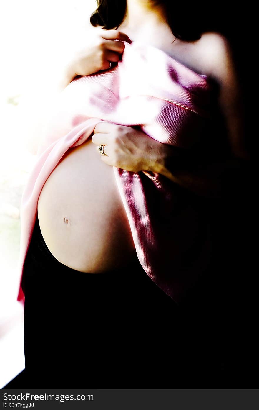 Pregnant woman belly exposed with pink wrap in window light trunk only