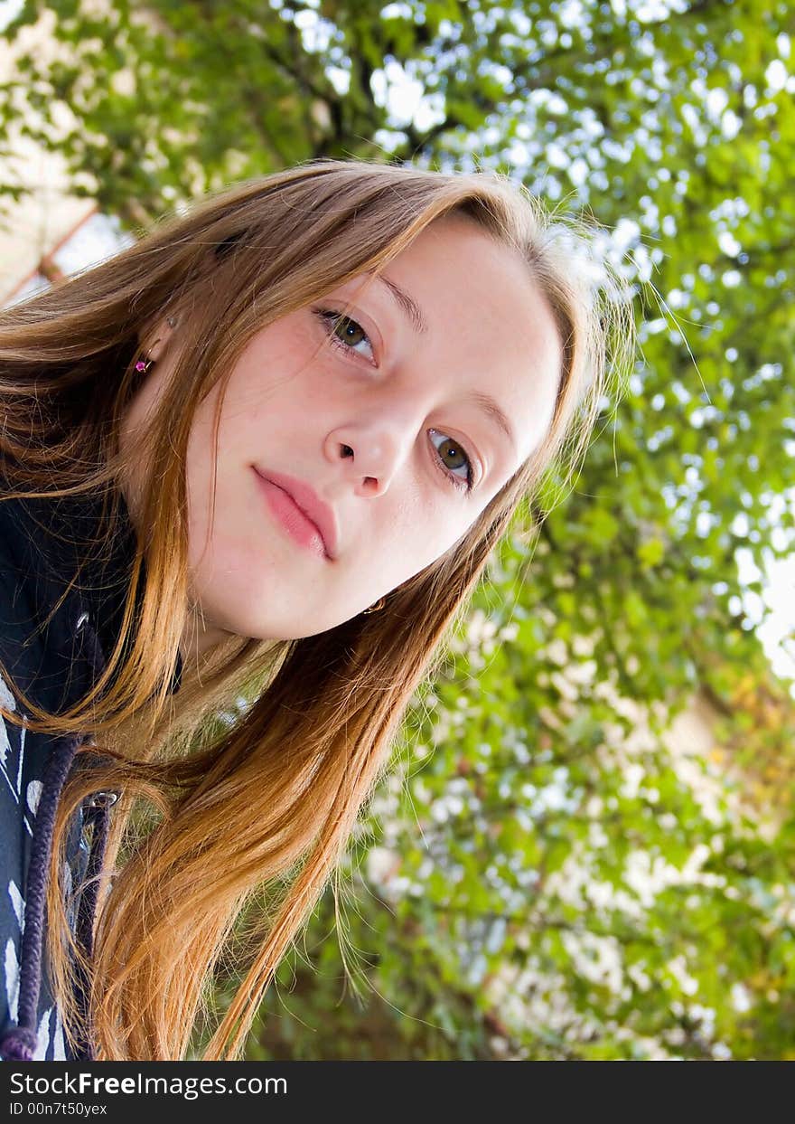 The lovely girl stands under a green tree. The lovely girl stands under a green tree