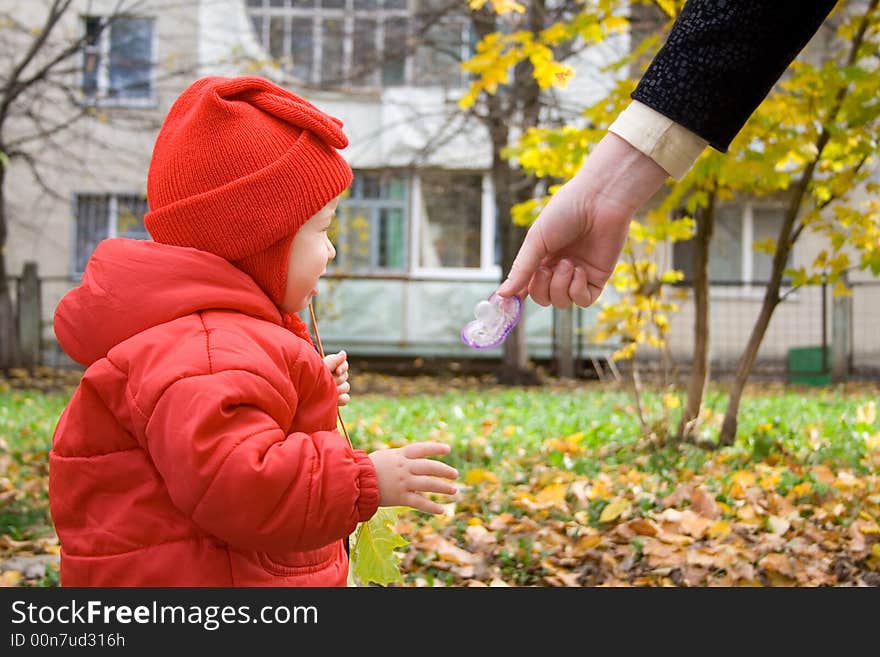 Baby in red shirt and mother hand with dummy. Baby in red shirt and mother hand with dummy