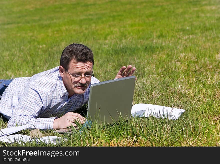 Businessman laying on the grass with his laptop and smiling :-). Businessman laying on the grass with his laptop and smiling :-)