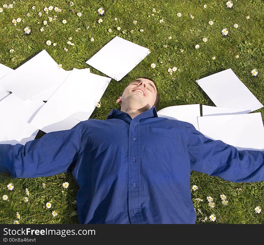 Businessman laying on the grass within his papers, happy and relaxed. Businessman laying on the grass within his papers, happy and relaxed.