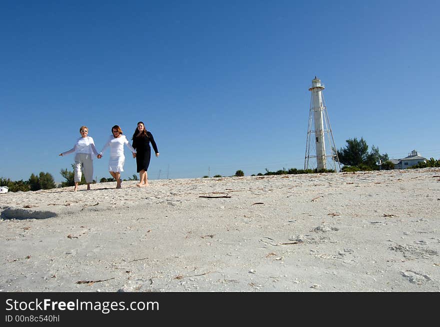 Three women of different generations walking along beach near lighthouse in Boca Grande Florida. Three women of different generations walking along beach near lighthouse in Boca Grande Florida