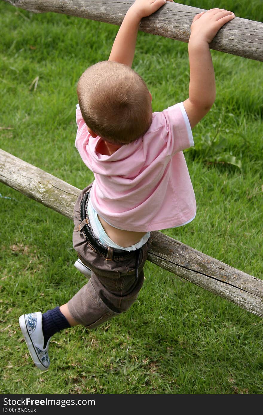 Young boy climbing on wooden fencing on a farm. Young boy climbing on wooden fencing on a farm