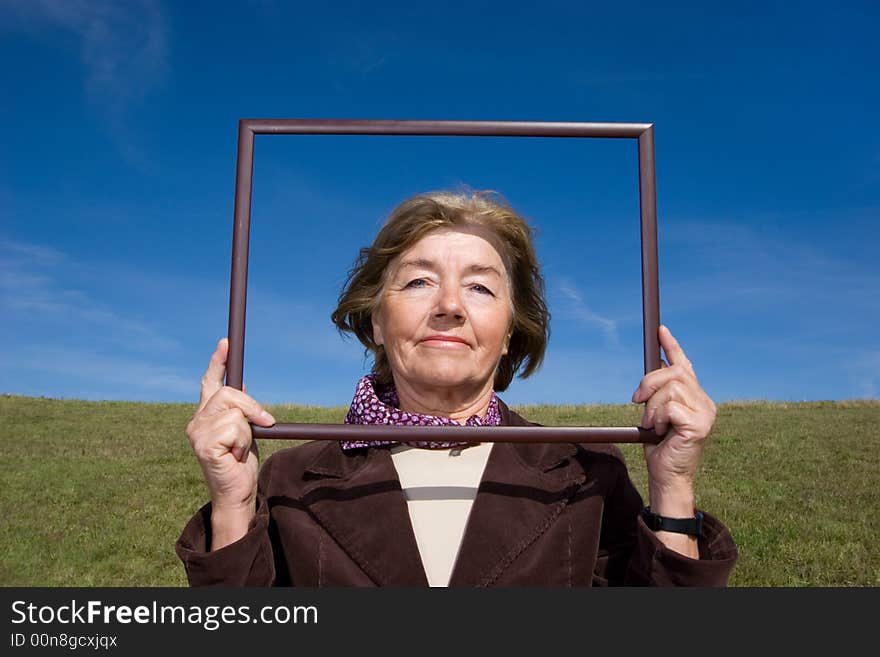 Mature and cheerful, joyful and happy woman enjoying life on a meadow - with a frame, where you can place your advertisement. Mature and cheerful, joyful and happy woman enjoying life on a meadow - with a frame, where you can place your advertisement.