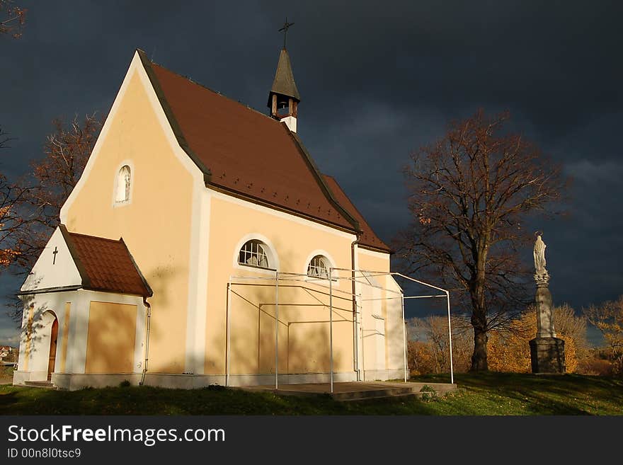 Yellow church with holy statue in front of dark blue sky. Yellow church with holy statue in front of dark blue sky