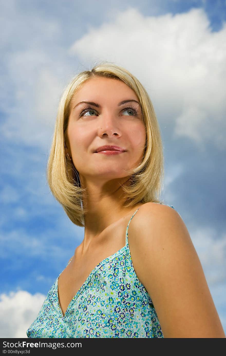 Beautiful blond girl and blue cloudy sky behind her