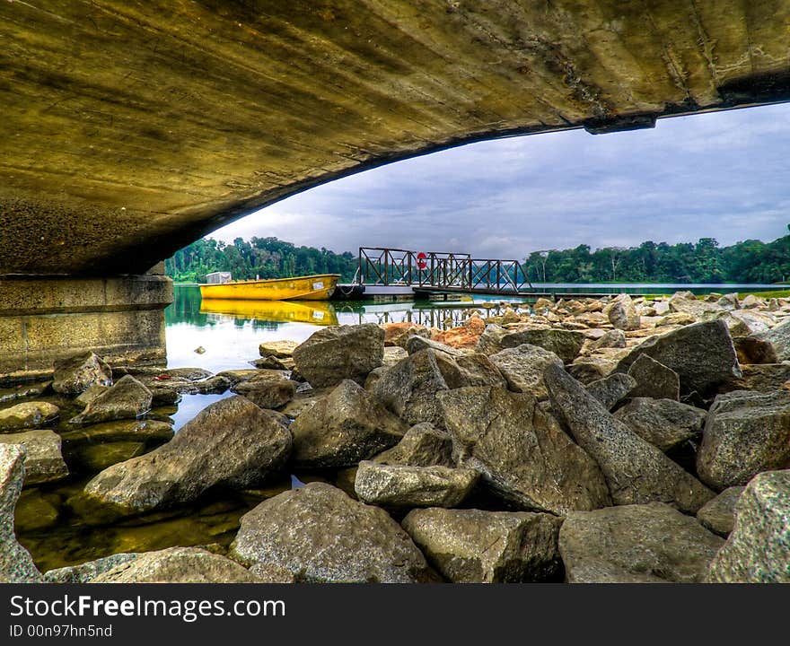 Boat moored to a jetty framed by the arching lines of the underside of a pier. Boat moored to a jetty framed by the arching lines of the underside of a pier