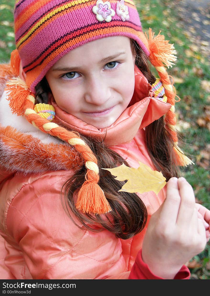 Girl holding small yellow leaf out in front of her. Girl holding small yellow leaf out in front of her