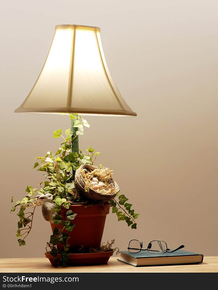 Closed book with reading glasses by a lit table lamp. Closed book with reading glasses by a lit table lamp.