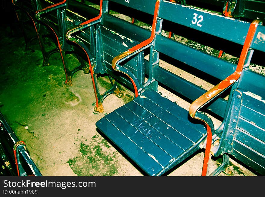 Stadium seating with green chipping paint and red arm rails