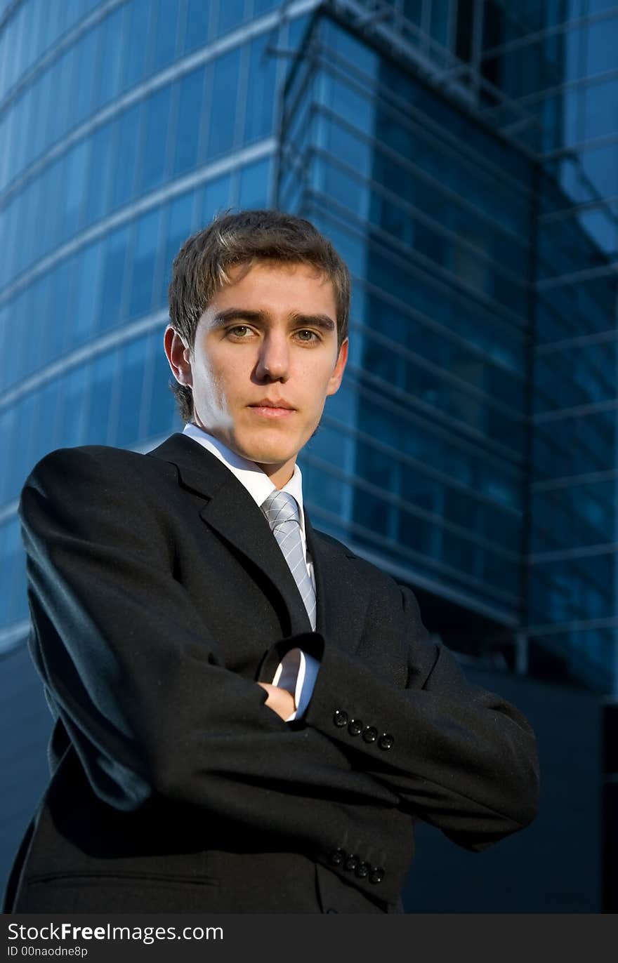 Young confident business man posing in front of office building