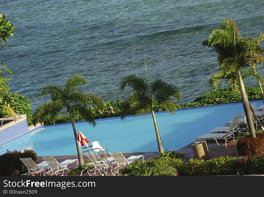 A hotel pool near the ocean shoreline. A hotel pool near the ocean shoreline.