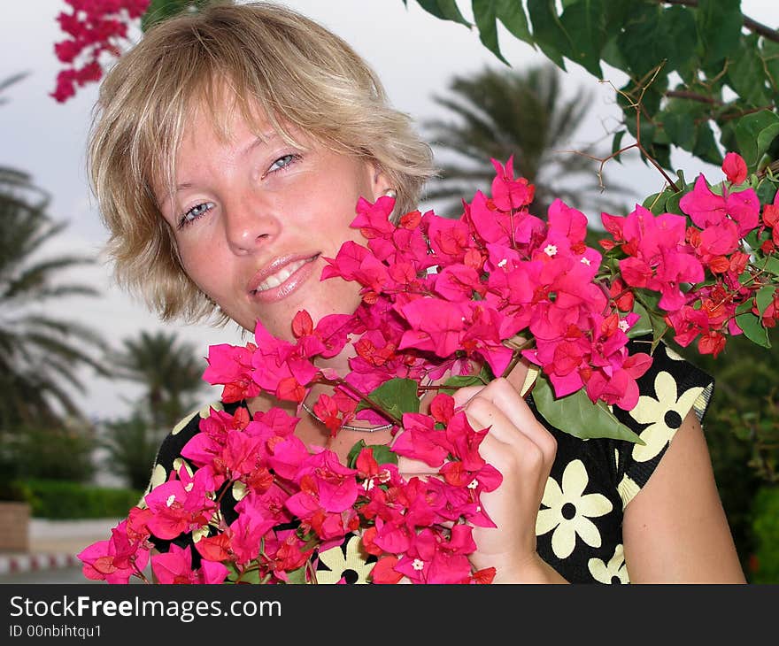 A beautiful blond girl and red flowers. A beautiful blond girl and red flowers