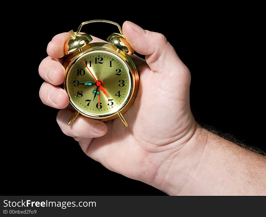 Alarm clock in a hand. Black background. The concept of time.