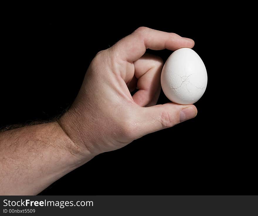 The hand holds an egg with cracks on a black background. The concept of destruction. The hand holds an egg with cracks on a black background. The concept of destruction.