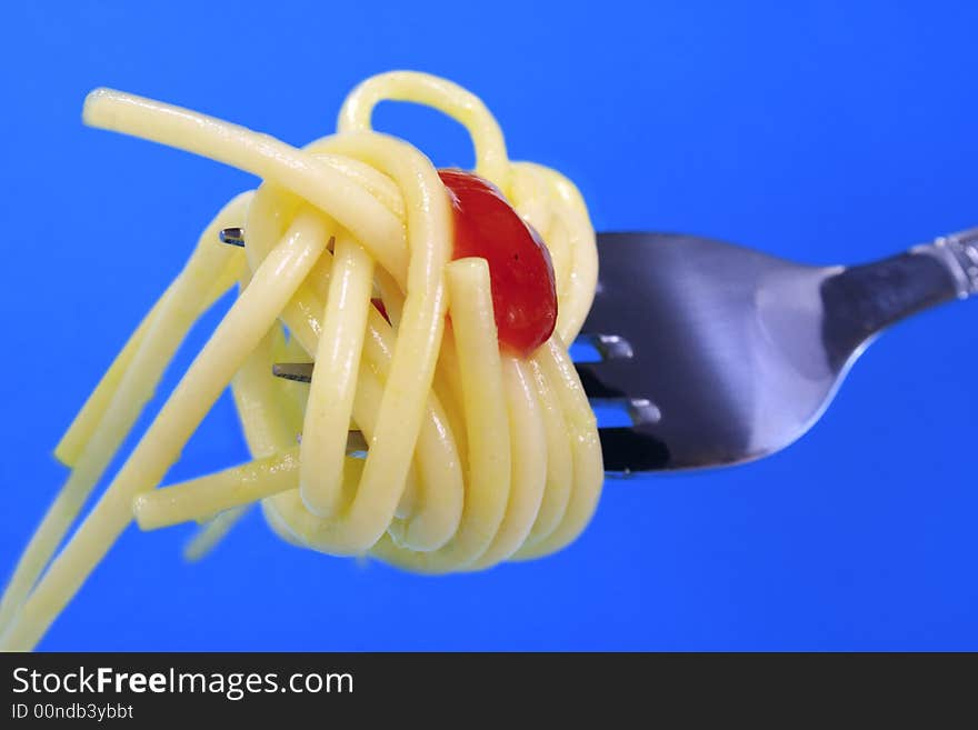 Pasta on fork on blue background