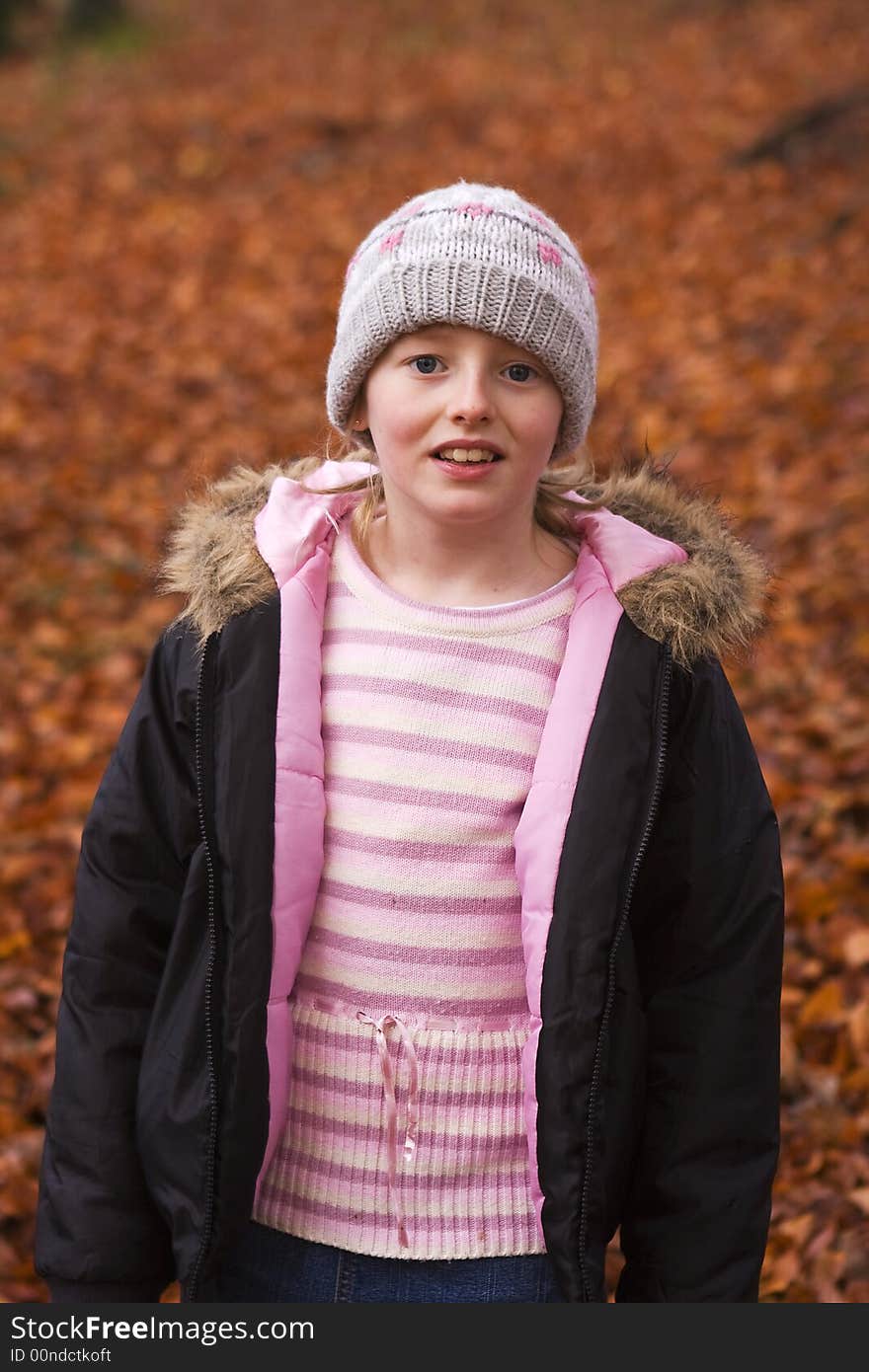 Girl in park surrounded by autumn leaves