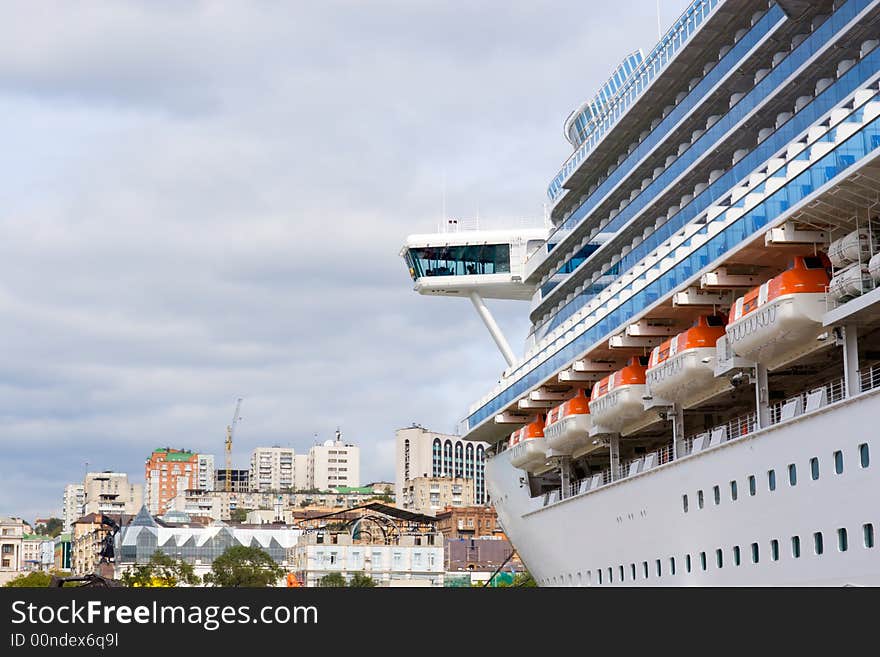 Russia. Round the world cruise ship is landing at pier in port Vladivostok. On a background there are houses of Vladivostok city. Russia. Round the world cruise ship is landing at pier in port Vladivostok. On a background there are houses of Vladivostok city.