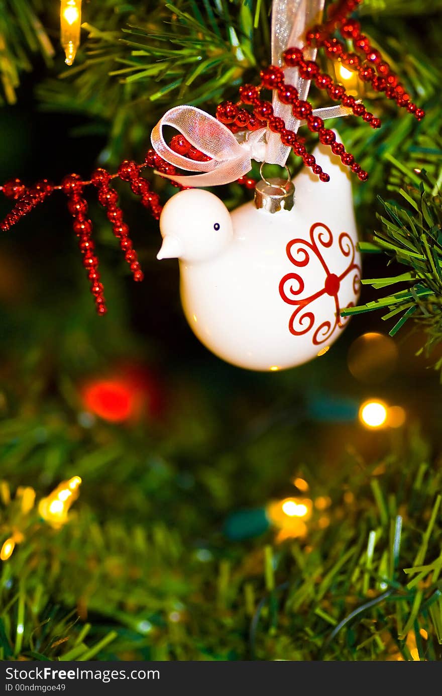 Dove ornament decorating a Christmas tree with other baubles and twinkling lights. Dove ornament decorating a Christmas tree with other baubles and twinkling lights