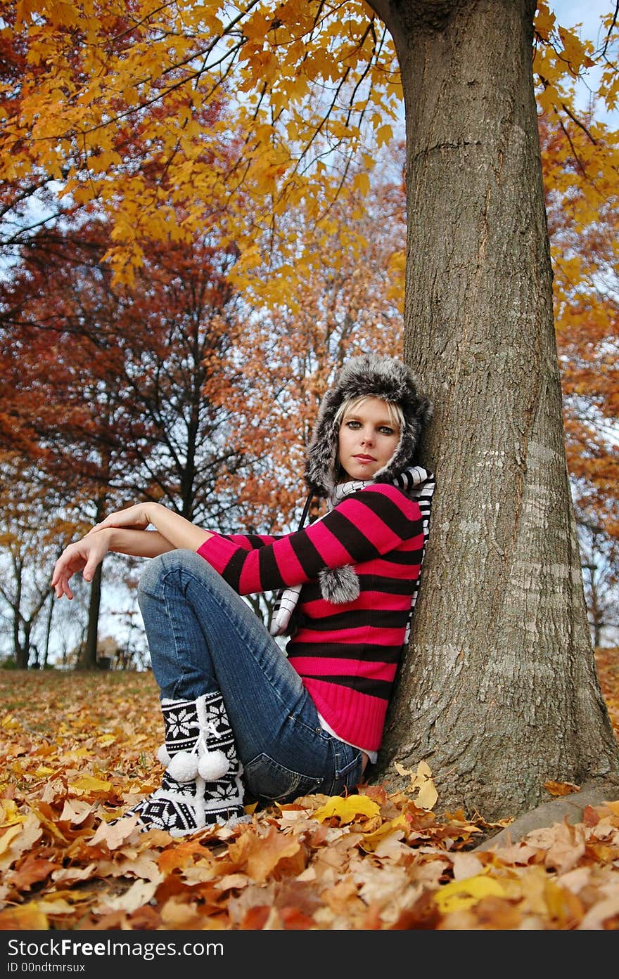 Beautiful girl resting against a tree on a fall day