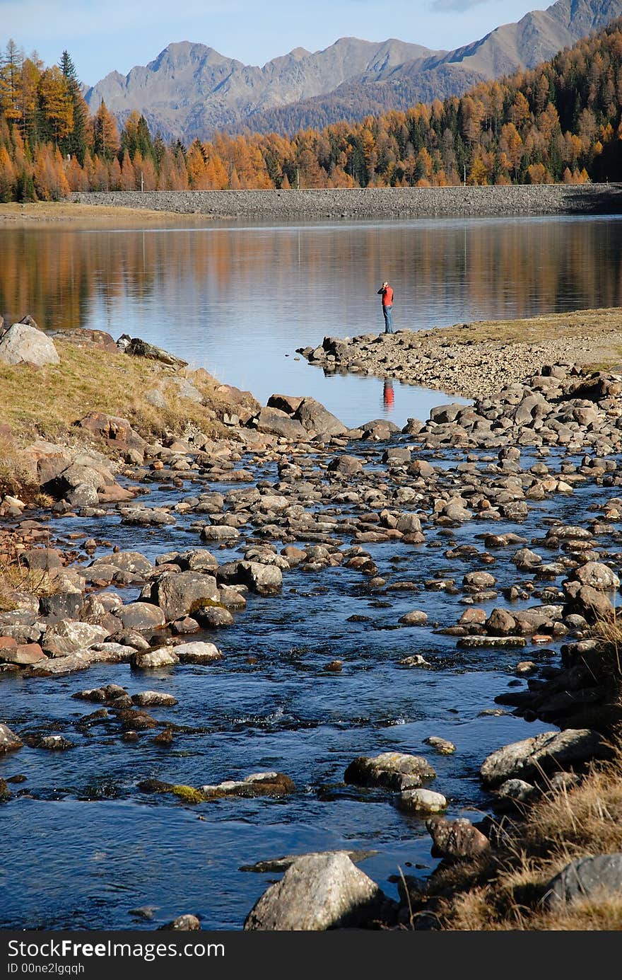 Lake with stream in high mountain, with a visitor looking in the water. Lake with stream in high mountain, with a visitor looking in the water.