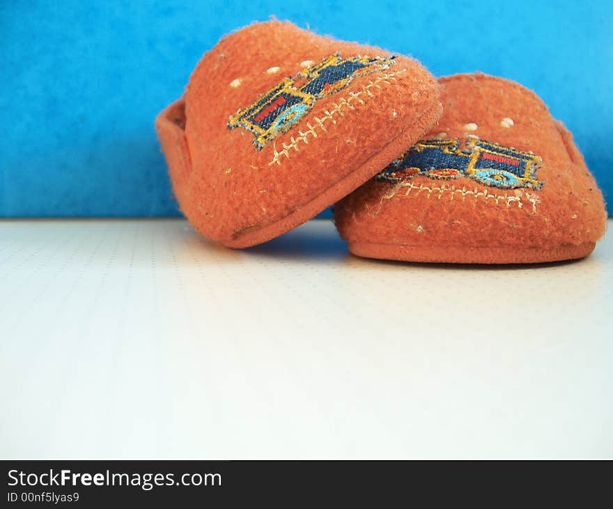 Orange worn baby slippers against blue background