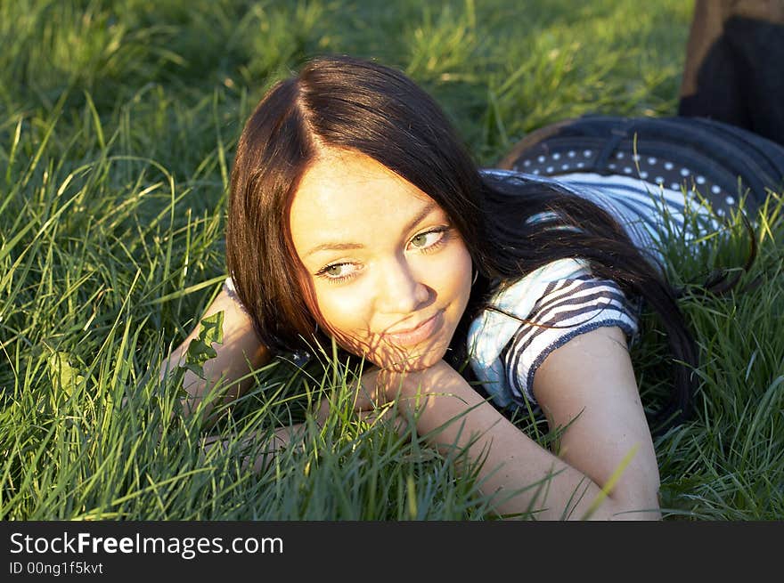 Teen girl lays on a grass