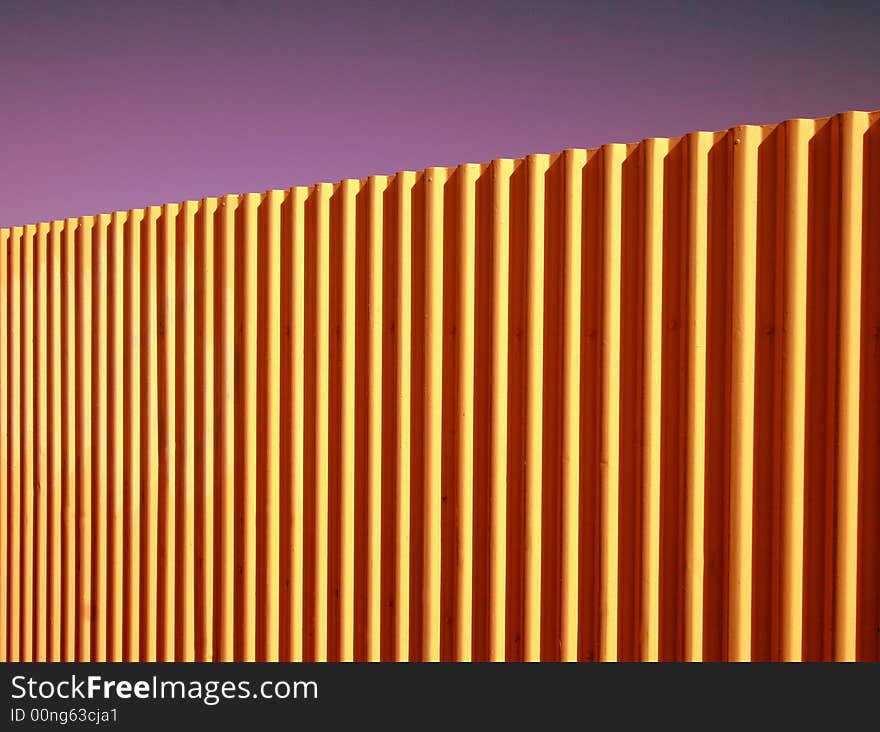 Bright coloured background of corrugated fence against a clear purple haze.