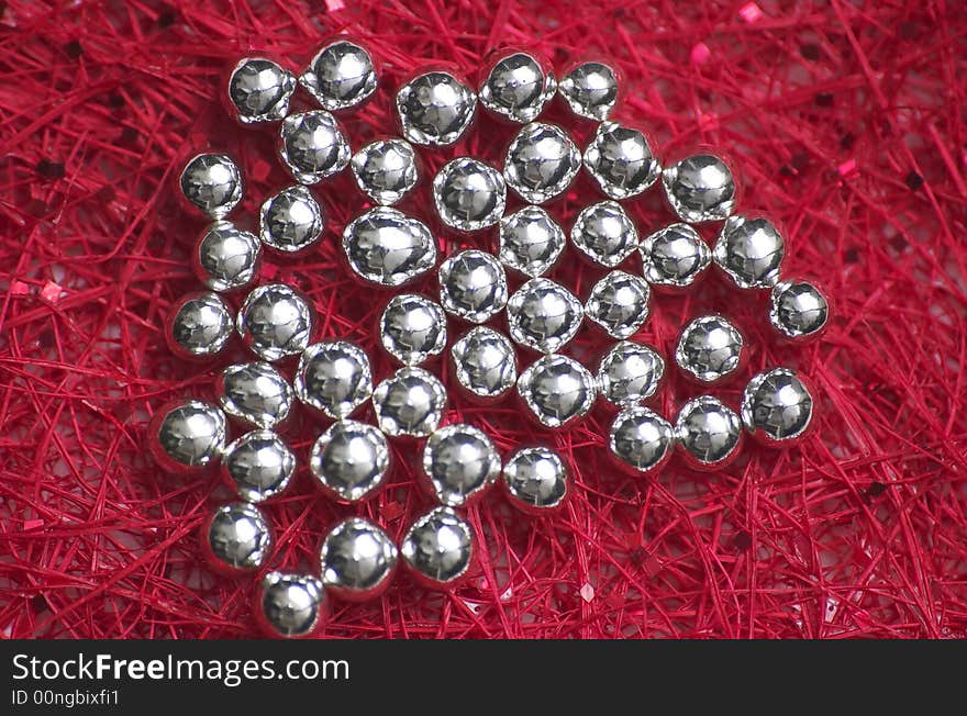 A piece of red fibre cloth forming an artificial pattern, with silver droplets on top. A piece of red fibre cloth forming an artificial pattern, with silver droplets on top