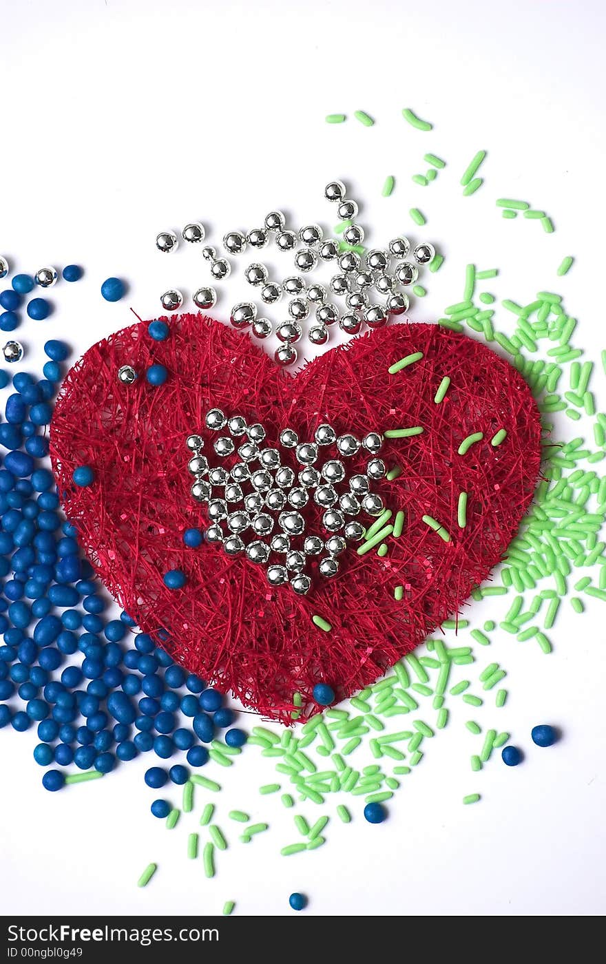 Three - coloured decoration made of silver, green and blue droplets with a heart-shaped red texture in the middle. Three - coloured decoration made of silver, green and blue droplets with a heart-shaped red texture in the middle