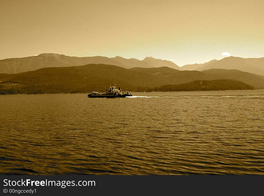 Sepia view of boat crossing lake in British Columbia, Canada