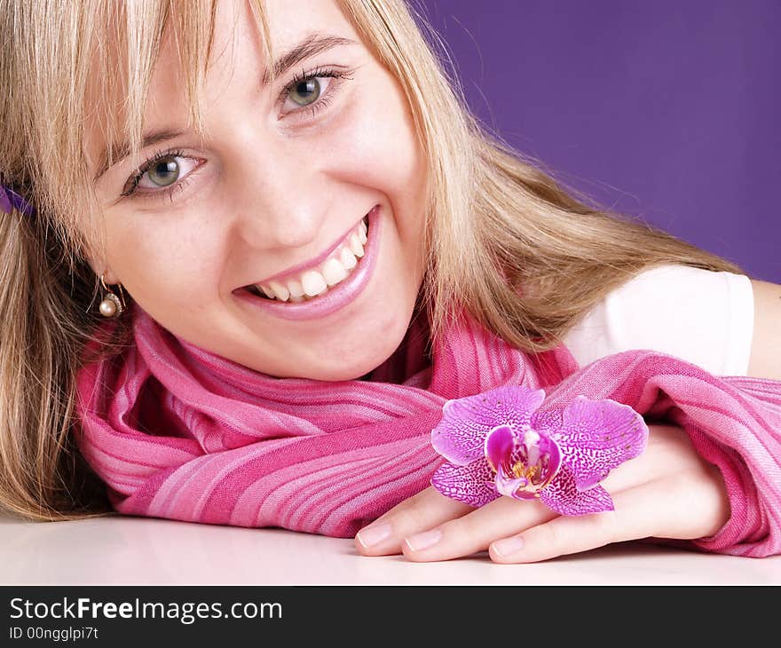 Smiling woman with orchid on the purple background.