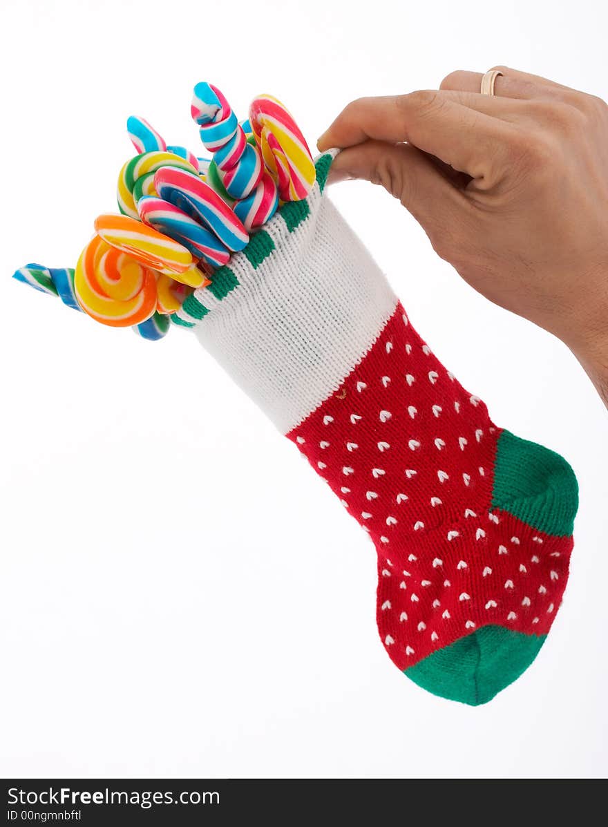 A hand holding a christmas stocking with lollipop candies inside. A hand holding a christmas stocking with lollipop candies inside