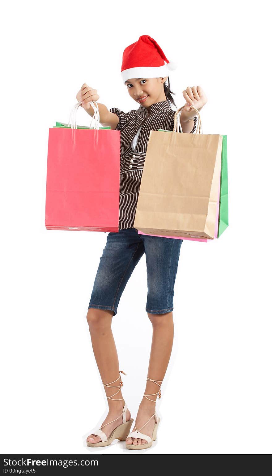 A girl wearing a christmas hat while holding some shopping bags