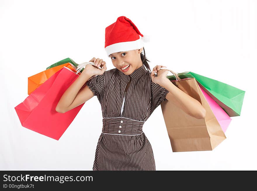 A girl wearing a christmas hat while holding some shopping bags