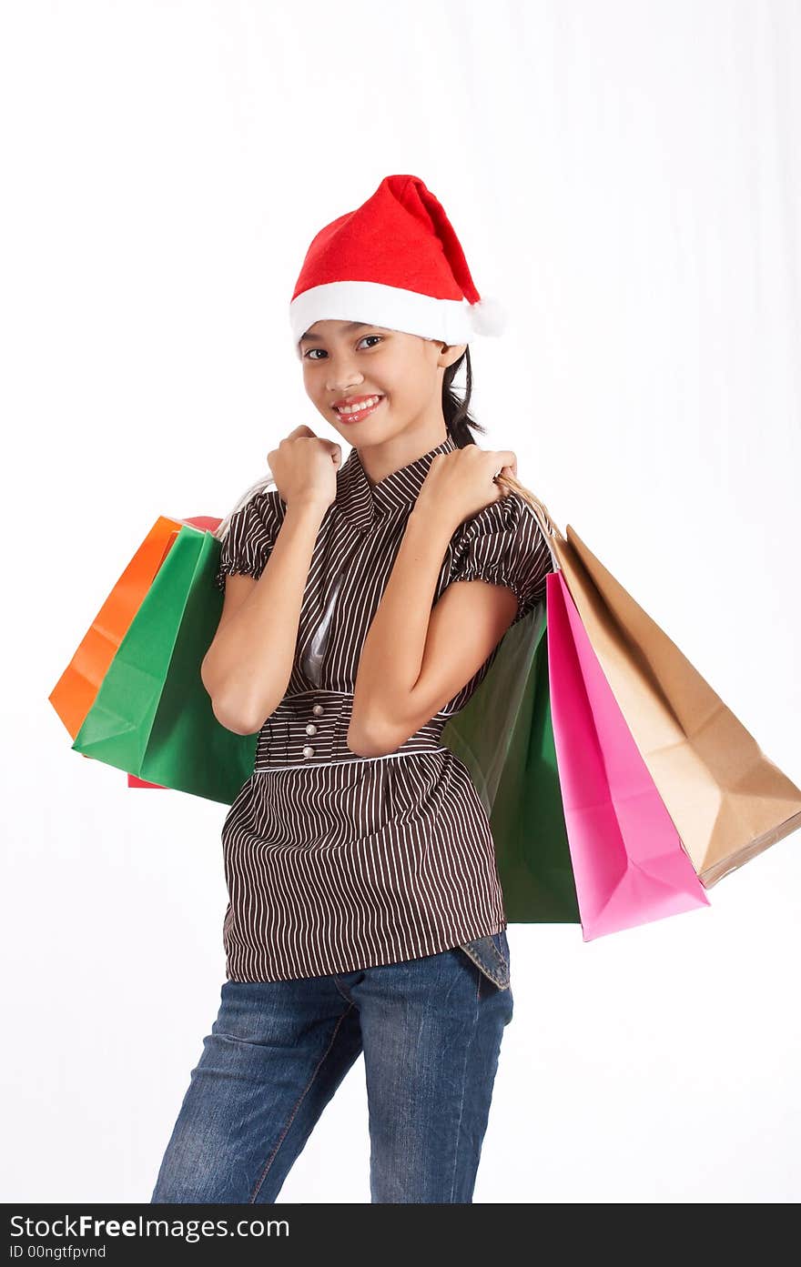 A girl wearing a christmas hat while holding some shopping bags